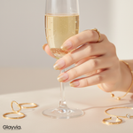Hand holding champagne glass showing gold glitter ombre nails with elegant nude base manicure