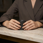 Close-up of hands wearing Glayvia metallic bronze semi-cured gel nail wraps holding a coffee cup.