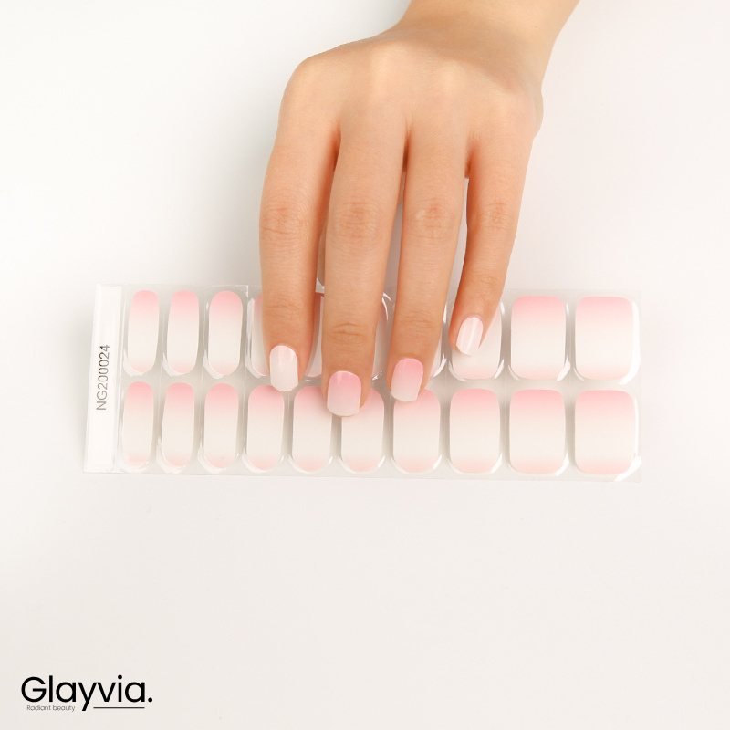 Hand wearing Glayvia NG200024 soft pink ombre semi cured gel nail wraps displayed above matching pink gradient nail wrap sticker sheet